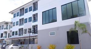 een wit gebouw met een auto ervoor geparkeerd bij Fun Hotel in Ban Thai Wat Khot