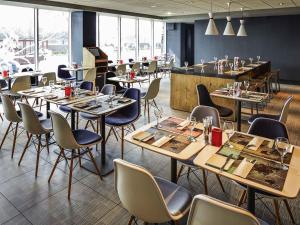 een restaurant met tafels en stoelen en een bar bij ibis London Heathrow Airport in Hillingdon