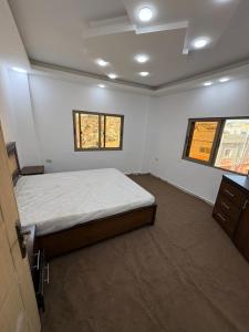 a bedroom with a bed and two windows at Golden Stay in Jerash
