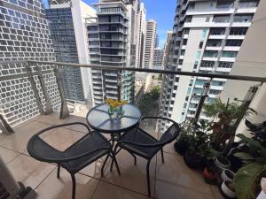 een glazen tafel en stoelen op een balkon met gebouwen bij Private Bedroom in Melbourne CBD in Melbourne