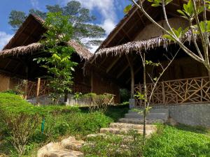 a house with a straw roof and stairs in front of it at Backpacker's Hill Resort in San Vicente