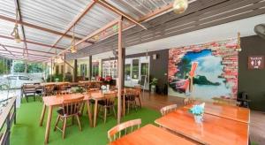 ein Restaurant mit Holztischen und Stühlen und einer Ziegelwand in der Unterkunft Royal Hill Satun Hotel in Ban Pak Ba Ra