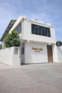 un bâtiment blanc avec une enseigne indiquant « cedar living » dans l'établissement Ceylon Lodge - Airport Transit Hostel, à Negombo