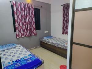 een kleine kamer met twee bedden en een spiegel bij Bageshree homestay in Guhagar