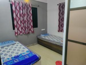 een kleine kamer met 2 bedden en gordijnen bij Bageshree homestay in Guhagar