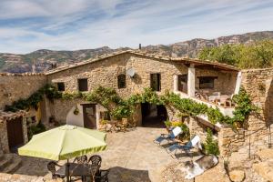 ein altes Steinhaus mit einer Terrasse mit Sonnenschirm in der Unterkunft Casa Mauri in Tremp