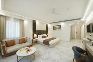 una stanza d'albergo con un letto, un divano e un tavolo di Hotel Ginger Palace Delhi Airport With Free Airport Pic Or Drop a Nuova Delhi