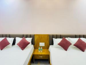 two beds in a hotel room with white and red pillows at Sairam Residency in Ellora +24 photos