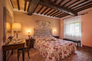 una camera con letto, tavolo e scrivania di Relais Osteria Dell'Orcia a Bagno Vignoni
