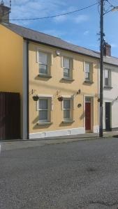 a yellow house with a red door on a street at The Retreat in Carlingford