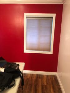 a bedroom with a red wall and a window at The Corner Suite in Norwalk