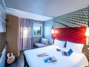 Schlafzimmer mit einem Bett mit einem Laptop und einer Gitarre in der Unterkunft Hotel ibis Porto Gaia in Vila Nova de Gaia