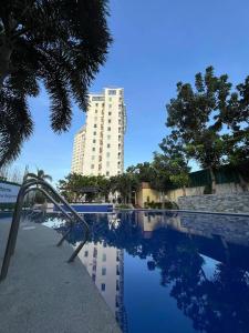 ein Schwimmbad mit einem hohen Gebäude im Hintergrund in der Unterkunft Staycation in Buli Muntinlupa in Manila