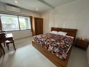 a bedroom with a bed and a desk and a window at Tebanyoman Guesthouse in Dalung