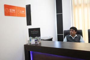 Ein Mann, der an einem Schreibtisch in einem Zimmer sitzt. in der Unterkunft Hotel Black Diamond, Zirakpur in Zirakpur