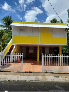 ein gelbes Haus mit einem weißen Zaun davor in der Unterkunft Casa Peace Haven Beach House Aguada in Aguada