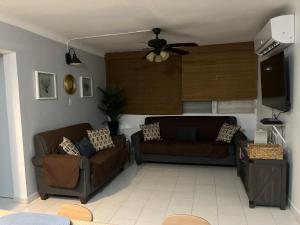 ein Wohnzimmer mit zwei Sofas und einem Flachbildfernseher in der Unterkunft Casa Peace Haven Beach House Aguada in Aguada