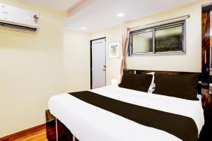 a bedroom with a large white bed with black pillows at Hotel O Metro Galaxy inn in Mumbai