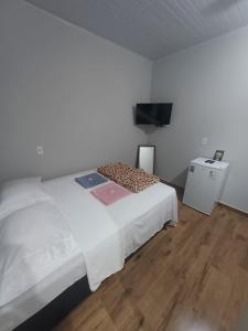 een slaapkamer met een bed en een flatscreen-tv bij Pousada São João in São Thomé das Letras
