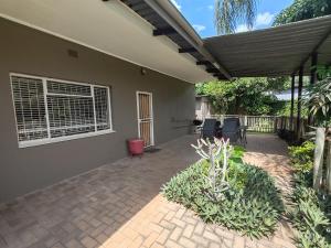 een huis met een terras met stoelen en een raam bij Ducks Nest in Malelane +35 foto's