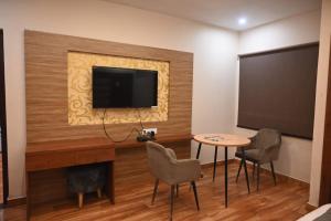 a room with a flat screen tv and a table and chairs at HOTEL UMA PALACE in Gorakhpur