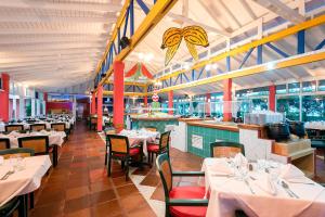 un restaurante con mesas y sillas blancas y un bar en Decameron San Luis - All Inclusive, en San Andrés