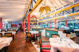 a restaurant with white tables and chairs and a bar at Decameron San Luis - All Inclusive in San Andrés