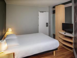 a bedroom with a large white bed and a television at Ibis Brussels City Centre in Brussels