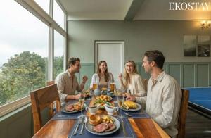 eine Gruppe von Menschen sitzt um einen Tisch herum und isst in der Unterkunft EKOSTAY I Pearl House Villa I 360 Degrees Tea Estate in Udagamandalam