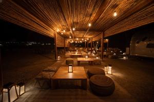 Eine Gruppe von Tischen und Stühlen unter einem Gebäude bei Nacht in der Unterkunft Nomad By Sharjah Collection in Kalbā
