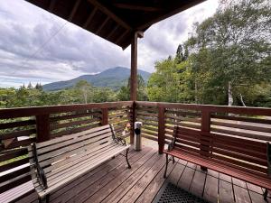 a porch with two benches and a view of mountains at Lodge ぷるーく in Myoko