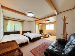 a bedroom with two beds and a living room with a couch at Lodge ぷるーく in Myoko +52 photos
