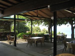 an outdoor patio with tables and chairs and the ocean at guest house kalamaki beach preveza in Rizá