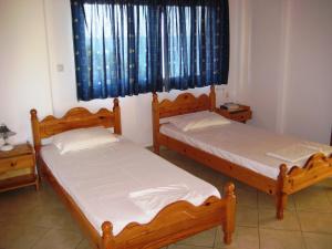 two twin beds in a room with a window at guest house kalamaki beach preveza in Rizá