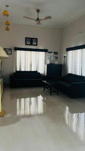 a living room with two black couches and a ceiling at Parthipuram in Thottada