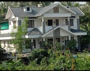 a large white house with a lot of plants at Parthipuram in Thottada