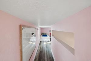 een roze kamer met een bed en een spiegel bij Quail Run Loft in Caldwell +13 foto's