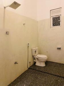 a bathroom with a toilet and a window at Emerald retreat in Ahangama