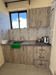 a kitchen with wooden cabinets and a sink at Lora's Haven Homes - Kikuyu Studio in Rungiri