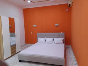 een bed in een kamer met een oranje muur bij Sakinu Appartement in Mahajanga
