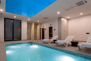 a swimming pool in a hotel with chairs at Qashqadaryo Hotel Olympic Village in Tashkent