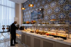 a man standing in front of a buffet line with food at Qashqadaryo Hotel Olympic Village in Tashkent