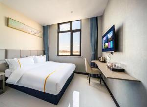 ein Hotelzimmer mit einem großen Bett und einem Schreibtisch in der Unterkunft Ruidenghao Hotel 24 hour free airport shuttle service from Shanghai Airport in Shanghai