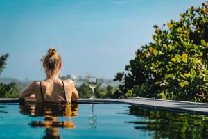 a woman sitting in a swimming pool with a glass of wine at Villa Hillcrest Weligama in Weligama