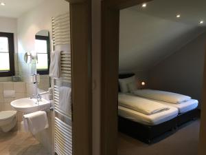 ein Schlafzimmer mit einem Bett und ein Badezimmer mit einem Waschbecken in der Unterkunft Landhaus Hotel Göke in Hövelhof