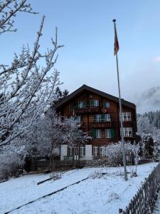a large wooden house with a flag in the snow at Staubbachbänkli in Wengen