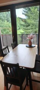 a wooden table with chairs and a vase of flowers on it at Apartmán Nest Brčálník in Železná Ruda