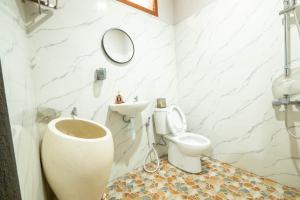 een witte badkamer met een toilet en een spiegel bij G Beach Hotel in Grajagan +37 foto's