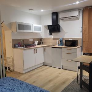 eine kleine Küche mit weißen Schränken und einem Tisch in der Unterkunft Riverside in Montereau-faut-Yonne