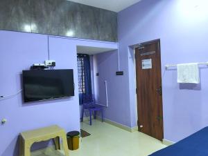 een kamer met een tv aan de muur en een deur bij ASSHAPPYSTAYINN HOTEL in Tiruchchirāppalli